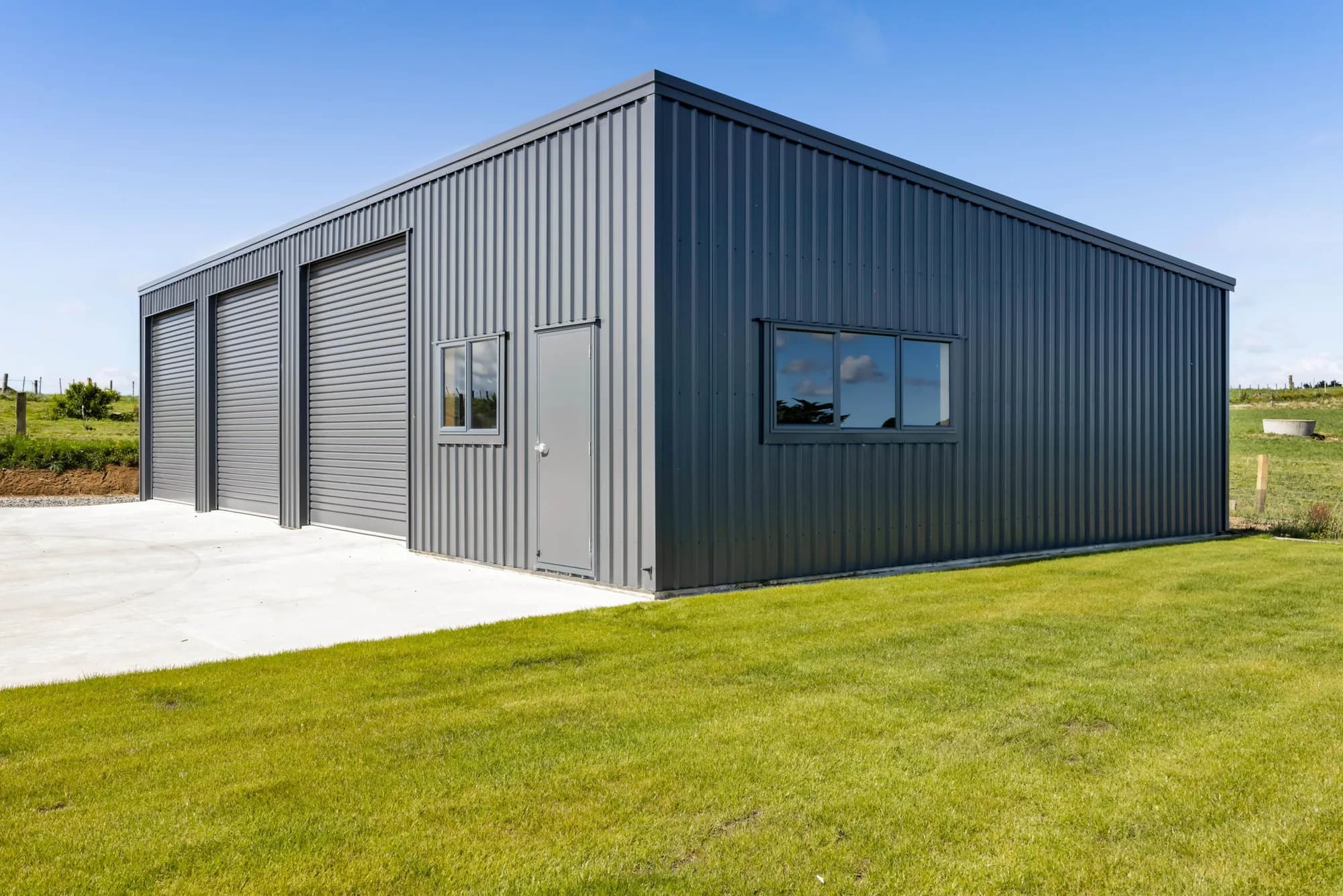 Three-bay residential garage with roller doors on a rural section